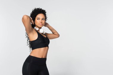 Güçlü, formda bir kadın kulaklıklarını düzeltirken aynı zamanda şık spor kıyafetlerine güvenir..