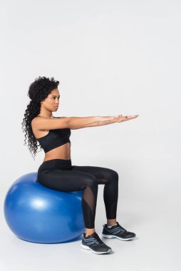 Formda bir kadın egzersiz seansında egzersiz topunda denge ve güç gösterisi yapar..