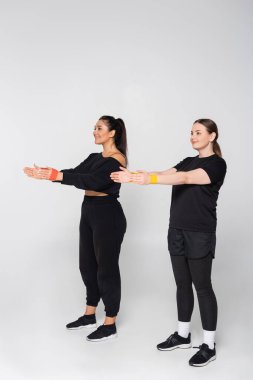 Formda olan iki kadın spor kıyafetlerini sergilerken kendilerine güvenerek fitness rutinleri üzerinde çalışırlar..