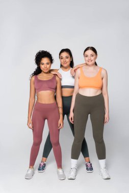 Üç güçlü, güzel kadın, birbirlerine güven içinde poz verirken fitness ruhlarını sergilerler..