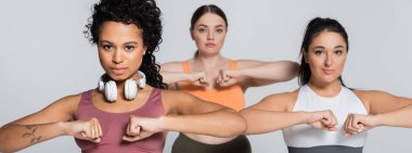 Güçlü bir fitness seansı sırasında üç kadın güçlerini ve odaklarını sergilerler..