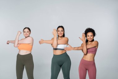 Üç güçlü ve zinde kadın birlikte spor yaparken atletizm gösterisi yapıyorlar..