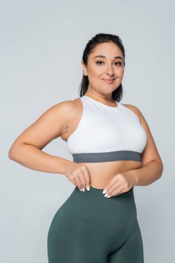 Kendine güvenen bir kadın şık spor kıyafetlerindeki güçlü fiziğini bir spor salonunda sergiliyor..