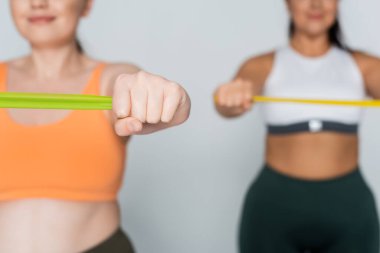 İki zinde kadın direniş bantlarıyla egzersiz yapıyor. Güç ve kararlılık gösteriyorlar..