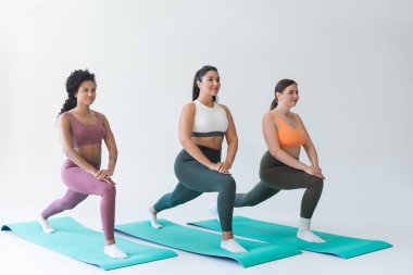Üç güçlü kadın renkli spor kıyafetleri içinde spor kıyafetlerini giyer ve birlikte spor gezileri düzenlerler..
