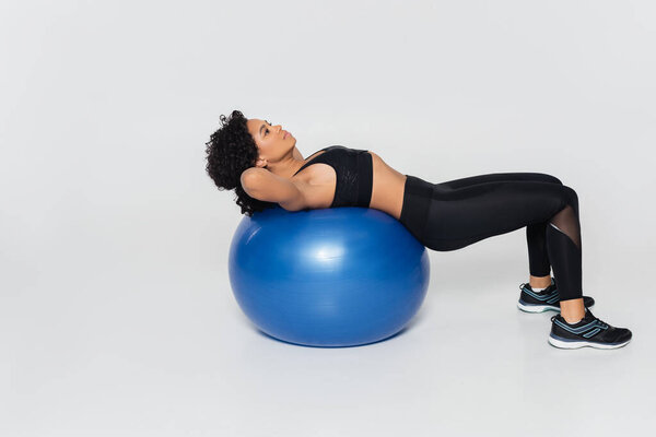 Strong woman engages in a fitness routine using a stability ball in a bright studio environment.