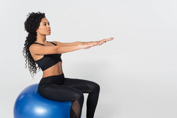 Подтянутая женщина в спортивной форме отлично балансирует на мяче во время тренировки..