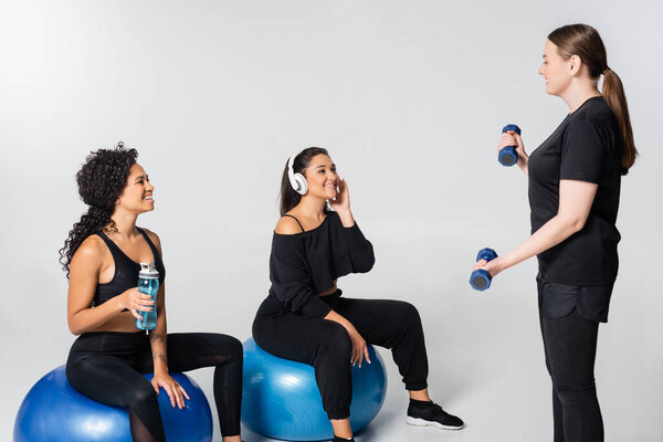 Three strong women enjoy an interactive fitness session, lifting weights together.