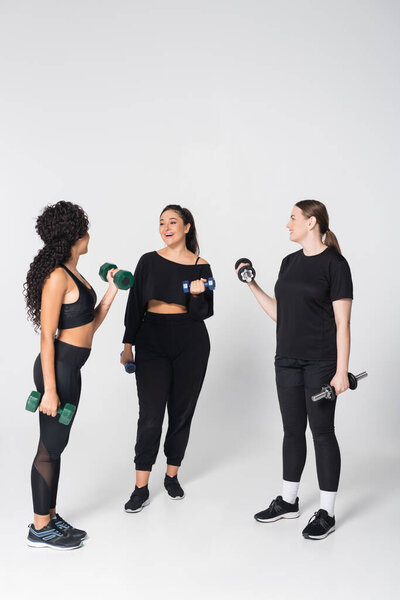 Three fit women enjoy a lively workout session while motivating each other in a spacious studio.