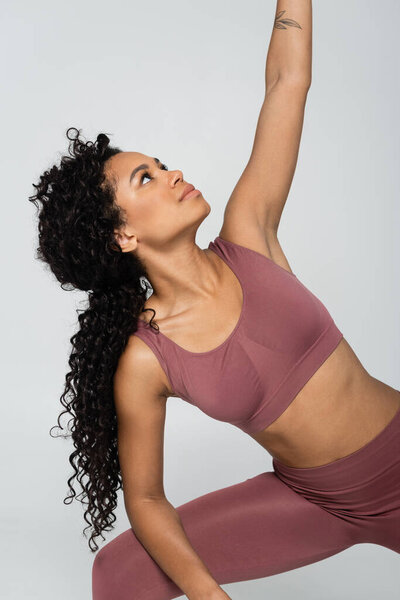 A fit woman performs a graceful fitness pose, showcasing strength and elegance in her workout gear.
