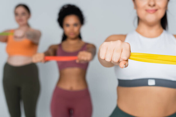 Подходящие женщины объединяются, выполняя упражнения с лентами сопротивления для силы и выносливости.