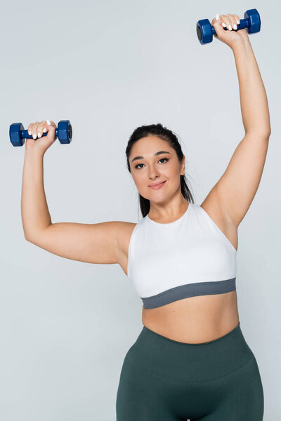 Сильная женщина участвует в динамичной тренировке, поднимая тяжести с уверенностью и изяществом.