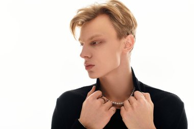 Genç, yakışıklı bir adam yakasını düzeltirken yumuşak ve parlak ışıkta moda anlayışını sergiliyor..