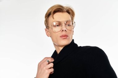 Genç bir adam dikkatlice uzaktan bakarken yakasını düzeltir..
