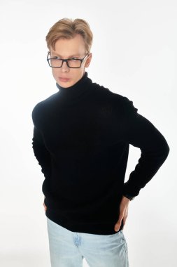 Genç adam, siyah süveter ve gözlükleriyle modern moda sergiliyor, karizma ve cazibe yayıyor..