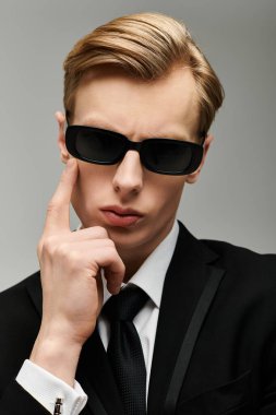 Özel dikim takım elbiseli ve güneş gözlüklü genç, yakışıklı bir adam kendine güven ve zarafet yayar..