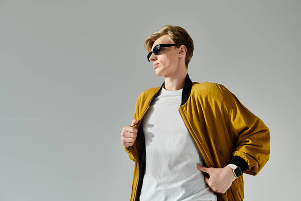 The young man poses confidently in a trendy bomber jacket and sunglasses.