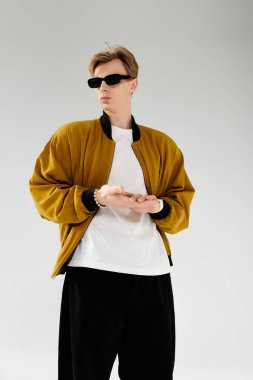 Moda kıyafetleri içinde genç bir adam kendine güvenerek duruyor, çağdaş moda ve tavır sergiliyor..