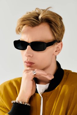 Güneş gözlüklü genç yakışıklı adam moda bir ceket ve aksesuar giyerken hayatı düşünüyor..