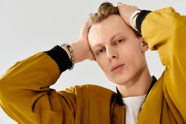 Genç bir adam çarpıcı özelliklerini ve moda anlayışını neşeli bir duruş ve sıcak bir gülümsemeyle sergiliyor..