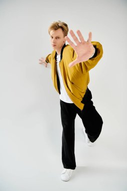Kendine güvenerek, genç ve yakışıklı bir adam dinamik bir duruş sergiliyor, modern moda seçimleri sergiliyor..