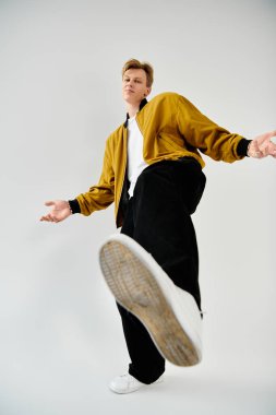 Bu genç adam şık kıyafetini sergilerken tarafsız bir arkaplanda rahatça poz veriyor..