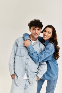 Two young friends show off their stylish denim outfits while playfully embracing in a chic space. clipart