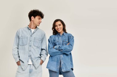 Genç çift, eşleşen kot kıyafetlerle, çağdaş moda atmosferleri yayarak rahatça poz veriyor..