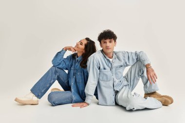 İki genç moda aşığı, modaya uygun kotlarını tarafsız bir zemine karşı sergiliyor..