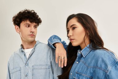 Tarafsız bir arkaplan karşısında şık kot elbiseli ikili poz veriyor.