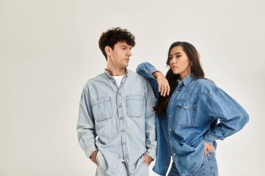 Tarz sahibi genç bireyler, minimalist bir arkaplana karşı modaya uygun kot kıyafetlerle rahatça poz verirler..