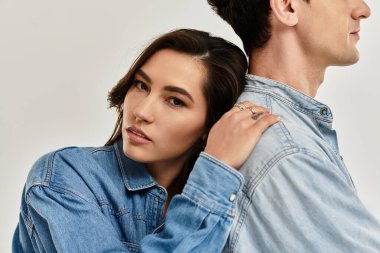 Genç bir çift kapalı mekanda birbirlerine yakın poz verirken şık kot tarzlarını sergiliyor..