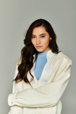 Tarz sahibi genç bir kadın, modern moda eğilimlerini sergileyen şık bir kıyafetin içinde özgüvenle poz veriyor..