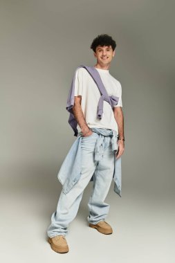 Young man poses confidently in trendy baggy pants and a layered casual top. clipart