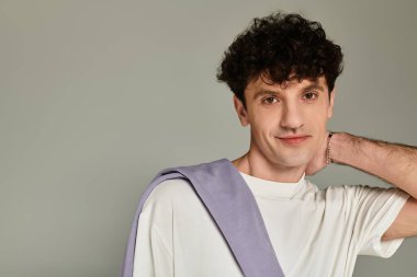 Genç, modaya uygun bir adam minimalist bir stüdyoda rahat ama şık bir şekilde poz verir..