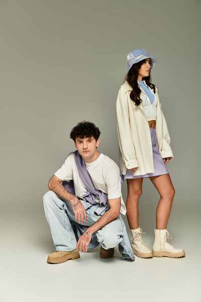 A fashionable couple poses confidently in trendy outfits, embodying youthful style and flair.