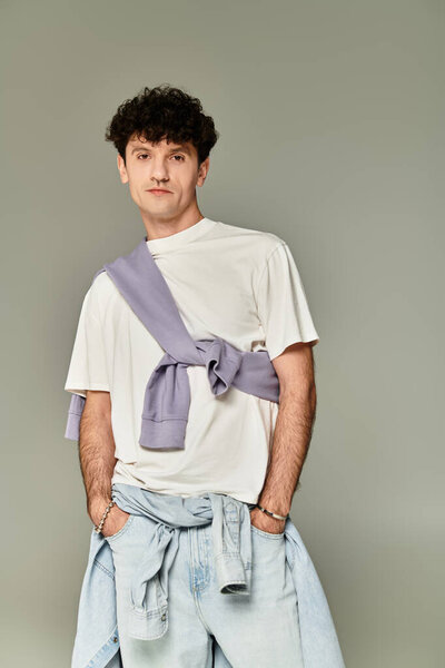 Fashionable young man stands confidently in a modern outfit, expressing contemporary style.