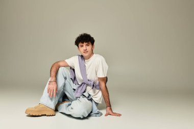 Genç bir adam şık, minimalist bir ortamda şık ve rahat poz verir..