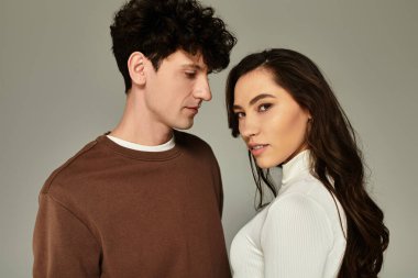 Tarafsız bir arkaplan karşısında şık giyinmiş genç bir çift poz veriyor..