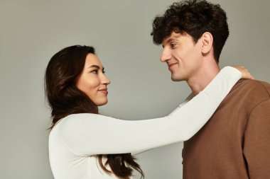 Şık bir genç çift, şık bir stüdyoda şık kıyafetlerini sergileyerek neşeyle kucaklaşır..