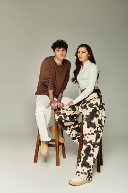 Şık bir çift modern bir mekandaki taburelerde şık kıyafetler ve zahmetsiz bir stil sergiliyor..