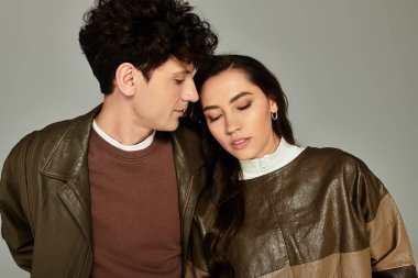 Genç çift, tarafsız bir zemin karşısında modaya uygun kıyafetler içinde modern zarafet sergiliyor..