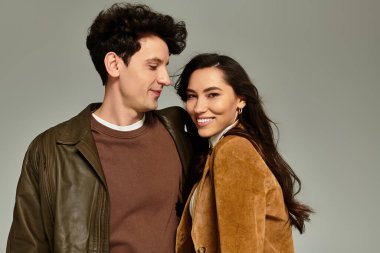 Genç bir çift, şık kıyafetler içinde, canlı bir şekilde birbirlerine gülümsüyor..