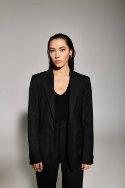 Tarz sahibi genç bir kadın şık siyah bir kıyafet giyer, moda anlayışını gösterir..