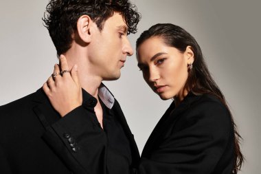 Genç çiftler birbirlerine yakın poz verirken kendilerine güvenen ifadelerle çağdaş moda sergilerler.