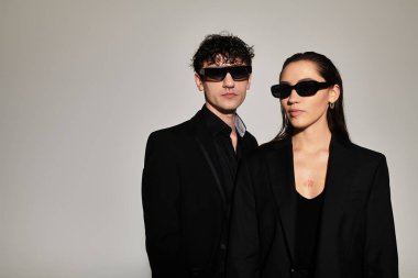 Genç çift, gösterişli siyah giysiler içinde, çağdaş zarafet ve stili somutlaştırarak dururlar..