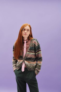 Canlı kızıl saçlı tuhaf bir genç, kendine güvenen bir şekilde rengarenk bir ortamda poz veriyor..