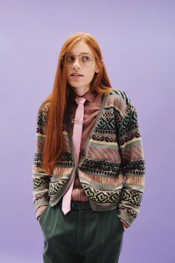 Uzun kızıl saçlı tuhaf bir adam canlı bir arkaplan önünde şık poz verir..