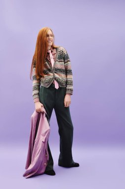 Modaya uygun, genç, tuhaf bir adam, mor bir arka plana karşı, kendine güvenen modaya uygun bir şekilde duruyor..