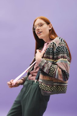 Uzun kızıl saçlı yakışıklı bir adam canlı bir arkaplana karşı güvenle poz veriyor..